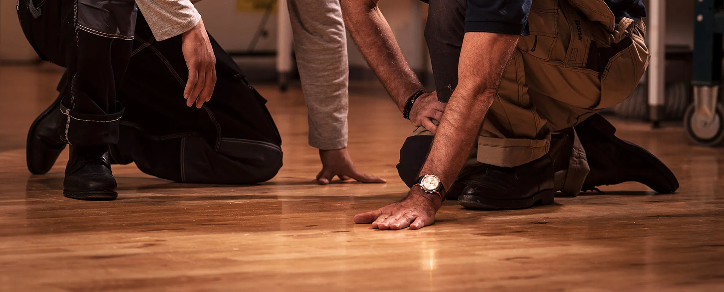 Hands checking the finish on a freshly restored hardwood floor.