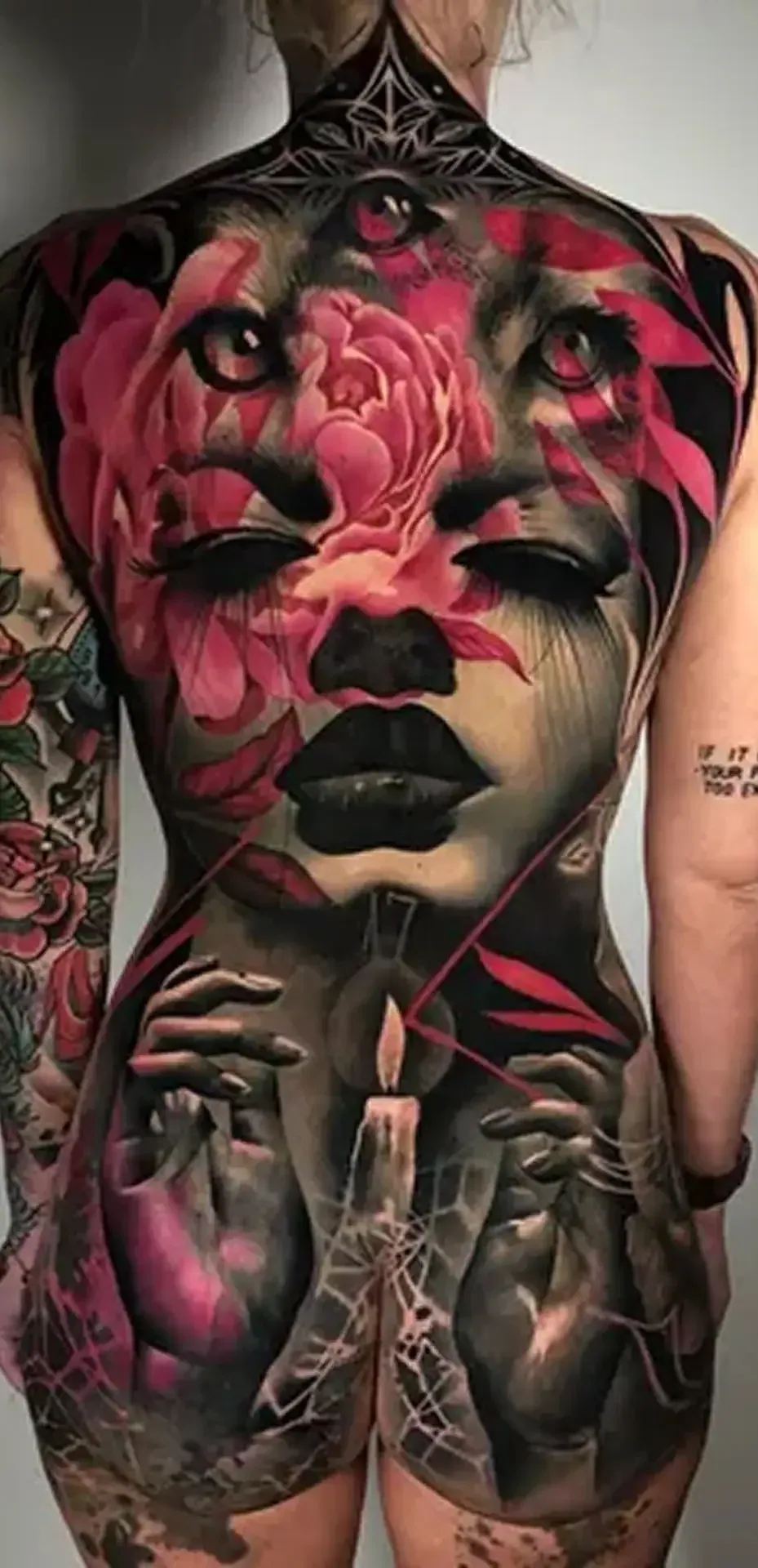 A back covered in a large color tattoo of a woman’s face and roses.
