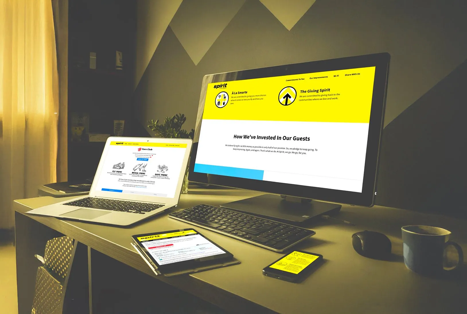 Spirit web pages open on a desktop, a laptop, a tablet and a phone in a dim room.