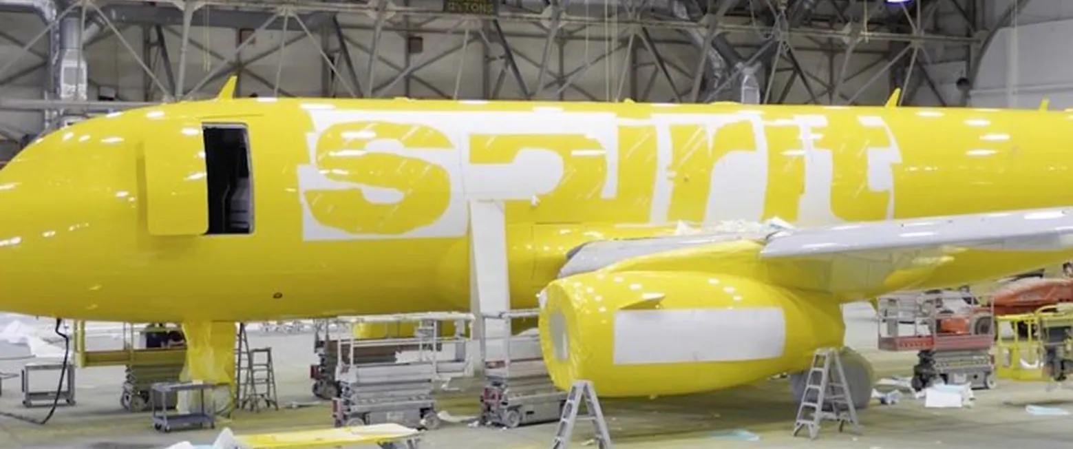 A Spirit jet in fresh yellow livery inside a hangar.